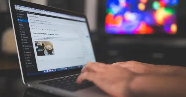 Persona trabajando en un portátil con gráficos de visitas y una libreta con ideas de contenido