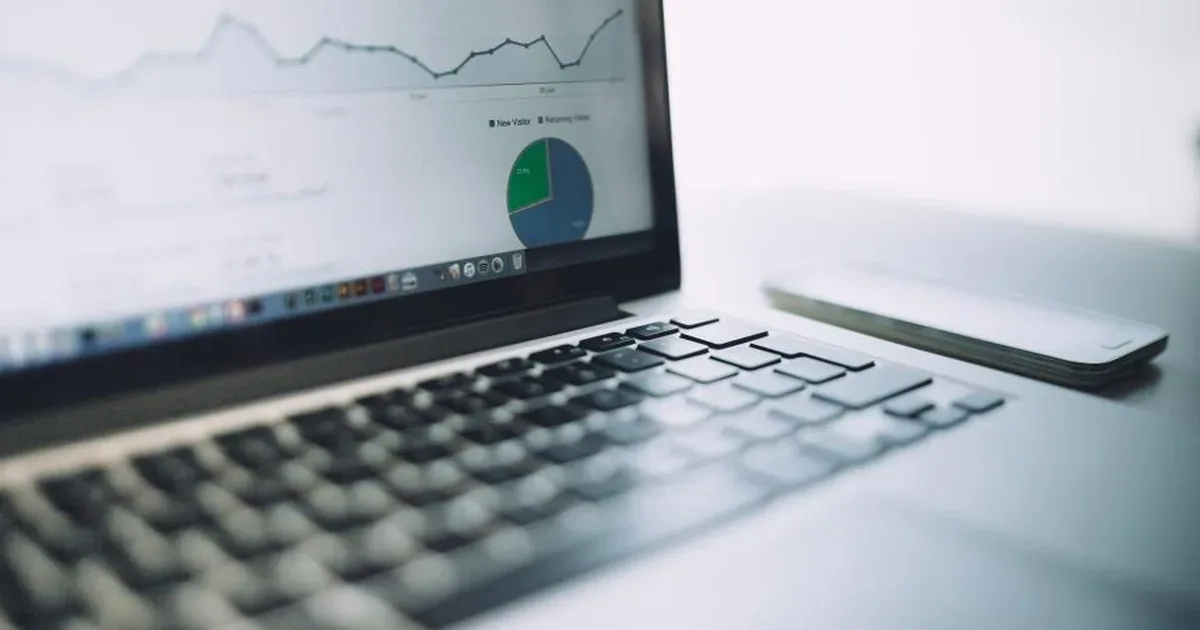 Persona analizando gráficos de analítica web en un portátil junto a una libreta con notas