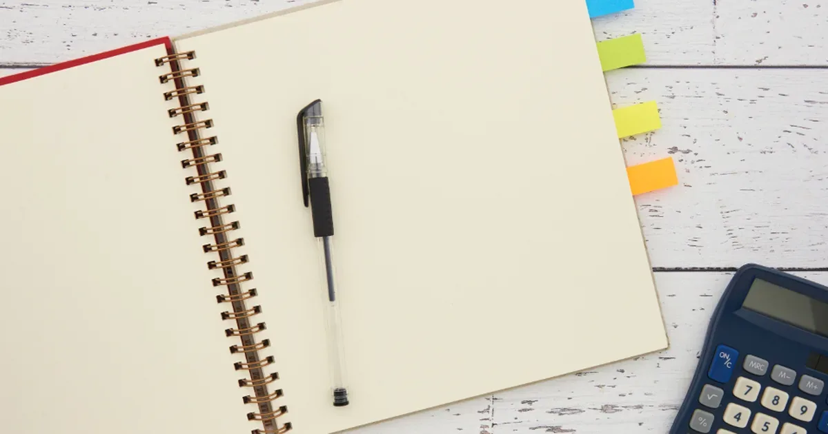 Mujer revisando sus cuentas y un presupuesto personal en un cuaderno junto al móvil