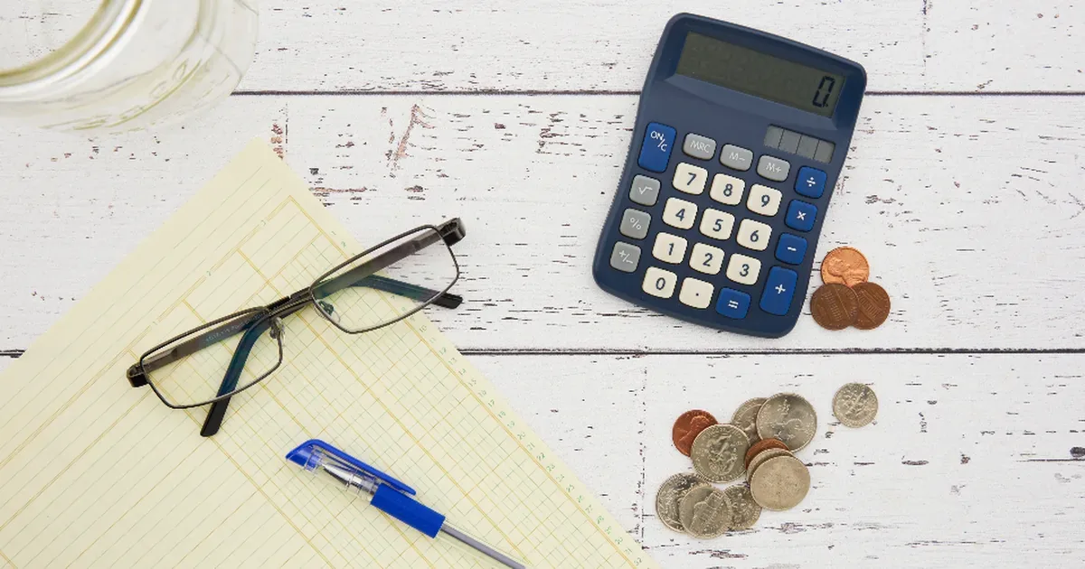 Persona organizando sus gastos e ingresos en una libreta junto a una calculadora