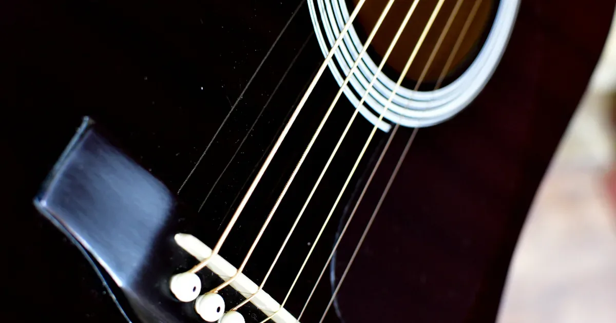 Guitarra acústica apoyada junto a una partitura y un cuaderno de notas musicales
