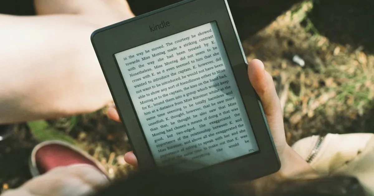 Tableta y lector electrónico con un ebook abierto junto a una taza de café sobre una mesa de madera